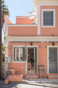 Well Apartments by Skyloft Corfu في Anemómylos: منزل وردي مع نافذة وباب