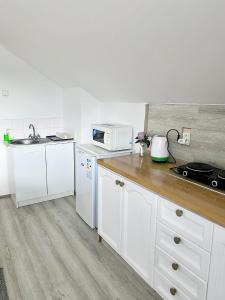 a kitchen with white cabinets and a sink and a microwave at Ubytovani v Beskydech in Bystrzyca
