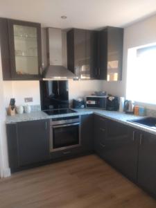 a kitchen with black cabinets and stainless steel appliances at Cheltenham - 3 Bed Newly Renovated With Parking in Cheltenham