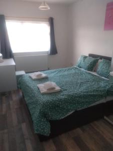 1 dormitorio con 1 cama con edredón verde y ventana en Cheltenham - 3 Bed Newly Renovated With Parking, en Cheltenham