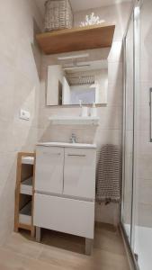 y baño blanco con lavabo y ducha. en Apartamento Sotavento Chipiona en Chipiona