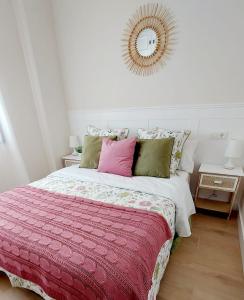 a bedroom with a bed with pink and green pillows at Apartamento Sotavento Chipiona in Chipiona