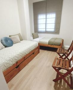 Habitación con 2 camas y una silla. en Apartamento Sotavento Chipiona, en Chipiona