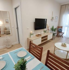a living room with a dining table and a television at Apartamento Sotavento Chipiona in Chipiona