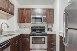 a kitchen with stainless steel appliances and wooden cabinets at BackBay Center Lux 2BR 2BA condo in Boston