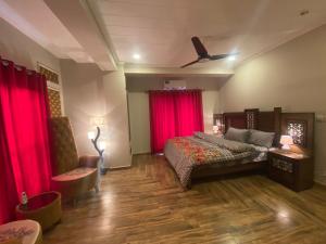um quarto com cortinas vermelhas, uma cama e uma ventoinha em De-Meridian Luxury Apartments em Rawalpindi