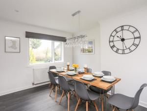 a dining room with a table and chairs and a clock at Ger Y Llan in Llangefni