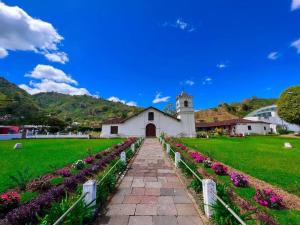 a church with a field of flowers in front of it at Orosi Mountain Lodge in Orosí