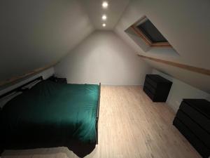 um quarto com uma cama verde num sótão em Ruim app. met grote garage em Ypres