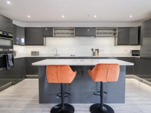 a kitchen with a island with two orange bar stools at The Bay Tree in Penrith