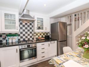 a kitchen with white cabinets and a stainless steel refrigerator at Anvil Cottage in York