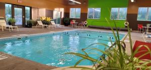 une grande piscine avec des chaises et des tables dans un bâtiment dans l'établissement Super 8 by Wyndham Plattsburgh, à Plattsburgh