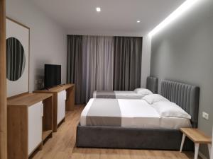 a bedroom with two beds and a flat screen tv at Te Aldo Hotel in Durrës