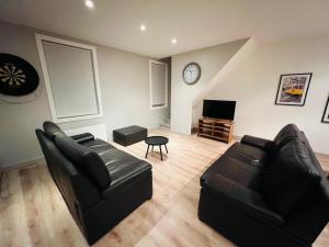uma sala de estar com mobiliário de couro preto e um relógio em Ruim app. met grote garage em Ypres