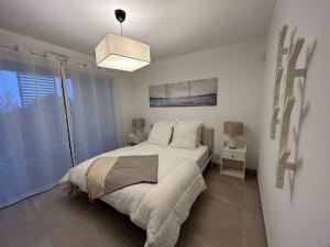 a white bedroom with a bed and a pendant light at Prestige View 411 in Èze