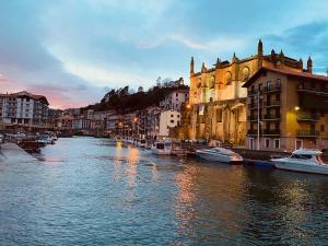 a river with boats in a city with buildings at Playa monte y mar, casa a 5 minutos del mar in Ondárroa