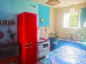 um frigorífico vermelho numa pequena cozinha com uma cama em TWO-BEDROOMS in GREEK VINTAGE HOME with shared Bathroom em Corinto