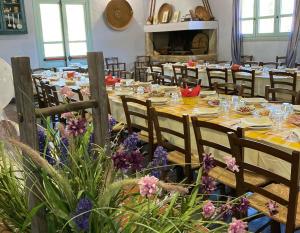 a dining room with long tables and chairs and flowers at Agriturismo Is Conchisceddas in Gonnosfanàdiga
