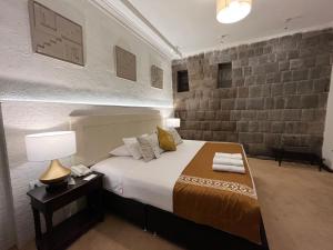 um quarto com uma cama, um candeeiro e uma parede de tijolos em Katari at Plaza de Armas Cusco em Cusco