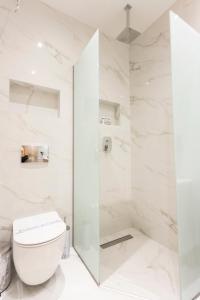 a white bathroom with a toilet and a shower at Eva's House in Afitos