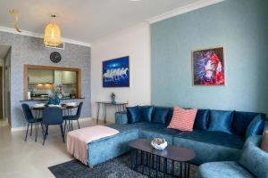 a living room with a blue couch and a table at Your 1BR Retreat on Yas Island Blue Sapphire Apartment in Abu Dhabi