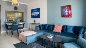 un soggiorno con divano blu e tavolo di Your 1BR Retreat on Yas Island Blue Sapphire Apartment a Abu Dhabi