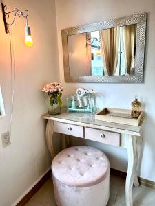 een badkamer met een wastafel met een spiegel en een roze kruk bij Freijoó Casa Vintage in Papantla de Olarte