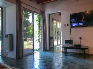 a living room with a large sliding glass door with a television at Relaxation Oasis in Chacras de Coria in Ciudad Lujan de Cuyo