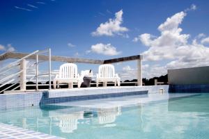 dos sillas blancas sentadas en el borde de una piscina en Be mas apartamentos boutique Valeria del Mar en Valeria del Mar