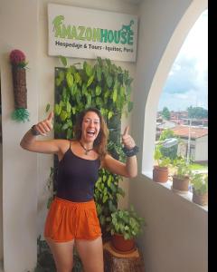 una mujer dando los pulgares delante de una señal en Amazon House Hostel en Iquitos