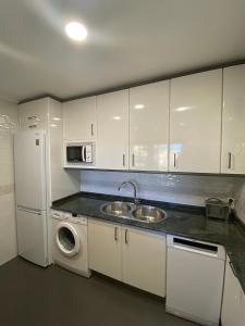 cocina con armarios blancos, fregadero y nevera en Apartamento Horia, en Viana