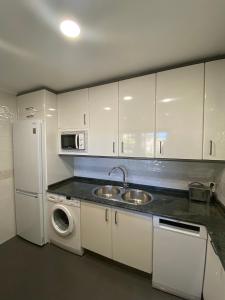 a kitchen with white cabinets and a sink and a refrigerator at Apartamento Horia in Viana