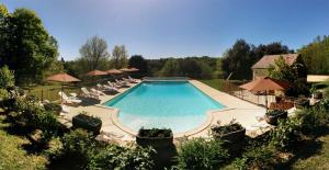 una gran piscina con sillas y sombrillas en Au Pré de l'Arbre, en Sarlat-la-Canéda