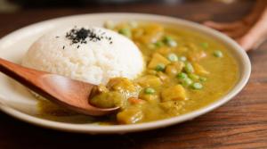 una ciotola di zuppa con riso e un cucchiaio di legno di Mohammadia Restaurant & Guest House a Dhaka