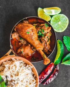 a plate of food with chicken and rice and limes at Mohammadia Restaurant & Guest House in Dhaka