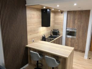 a kitchen with a counter with two chairs and a sink at JAB Apartments Bandurskiego Business & Family in Szczecin