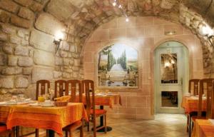 a restaurant with tables and chairs in a stone wall at Hotel Louvre Sainte Anne in Paris