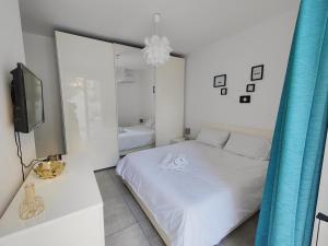 a white bedroom with a bed and a tv at Large Central Apartment Near Valletta & Seafront in Pieta