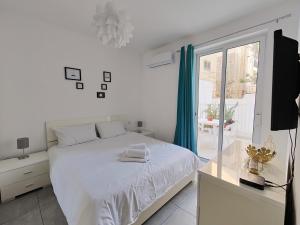 a white bedroom with a white bed and a window at Large Central Apartment Near Valletta & Seafront in Pieta