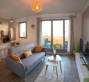 uma sala de estar com um sofá e uma mesa em Cosy appartement avec vue sur Genève em Collonges-sous-Salève