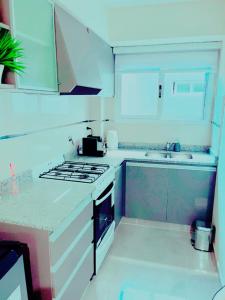 a kitchen with white cabinets and a stove top oven at LUMIÈRE ALICAR APPTS &SUITES in Buenos Aires