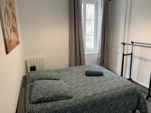 Un dormitorio con una cama con una manta y una ventana. en misoev, en Cherbourg-en-Cotentin