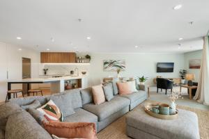 a living room with a couch and a kitchen at Executive Oceanside Apartment in Mount Maunganui