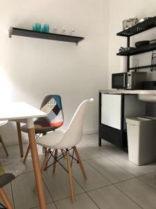 una cocina con 2 sillas blancas y una mesa en Quattro Casa en Sopron