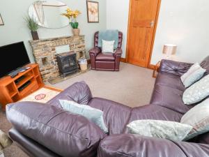 sala de estar con sofá de cuero y chimenea en Trelydarth en St. Agnes 