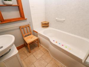 a bathroom with a tub and a chair and a sink at Trelydarth in St. Agnes 