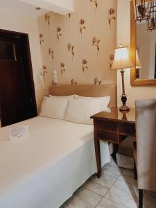 a bedroom with a bed and a desk with a lamp at Five Seasons Pension in Nafplio