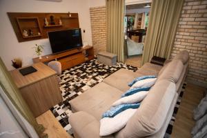ein Wohnzimmer mit einem Sofa und einem Flachbild-TV in der Unterkunft Casa de Campo, Refúgio do Lago in Itajaí