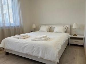 een wit bed met witte handdoeken erop bij Elegant Escape apartment II - City Centre in Bratislava