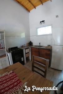 een keuken met een tafel, een koelkast en een fornuis bij La ponferrada in Villa Ventana